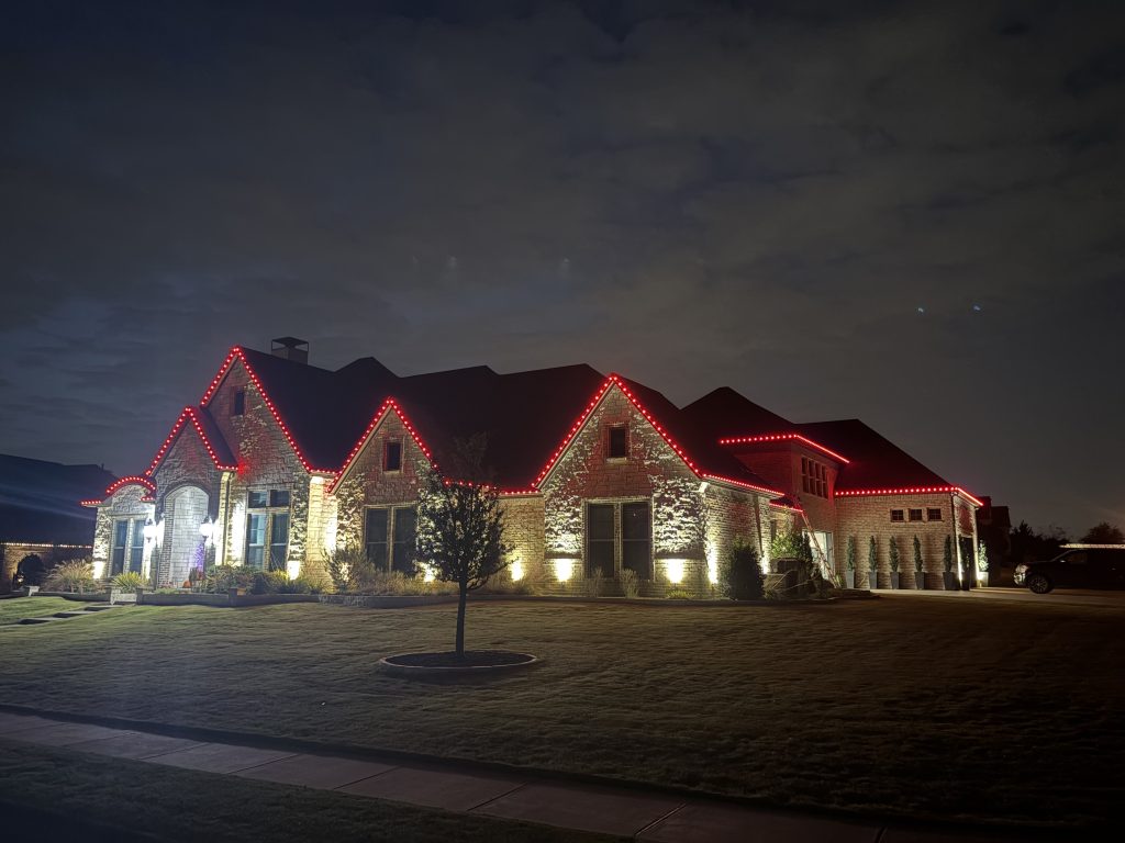 Iso view of a large modern home showing red LED lights along all rooflines at night