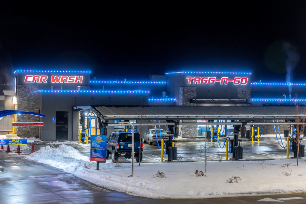 Commercial car wash with bright blue LED roofline lights at night